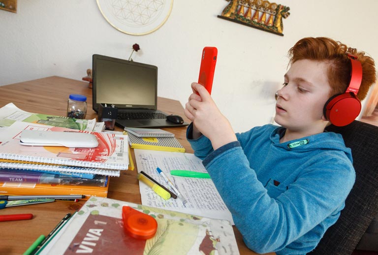 Junge macht Hausaufgaben Junge macht seine Hausaufgaben und lernt mit Handy.