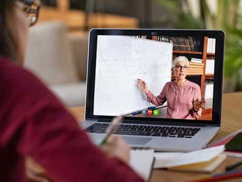 Ein Schüler sitzt vor einem Laptop, auf dem ein Lernvideo läuft.