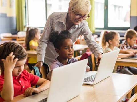 Lehrerin unterrichtet ihre Schüler:innen am Laptop.
