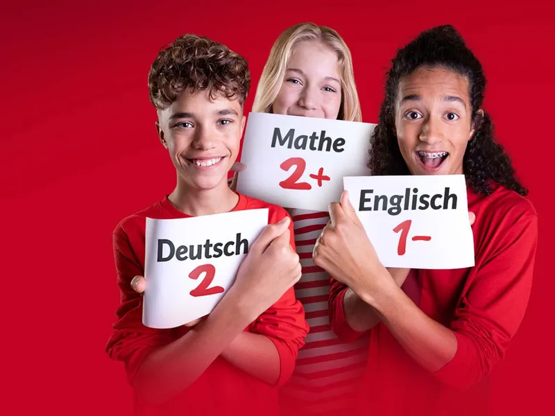 Drei Schüler halten Zettel mit den Noten Deutsch 2, Mathe 2+ und Englisch 1− in die Kamera.