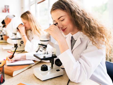 Schülerinnen im Chemieunterricht mit Mikroskop.