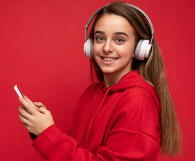 Schülerin mit Kopfhörern und Handy nutzt online Lernangebote.